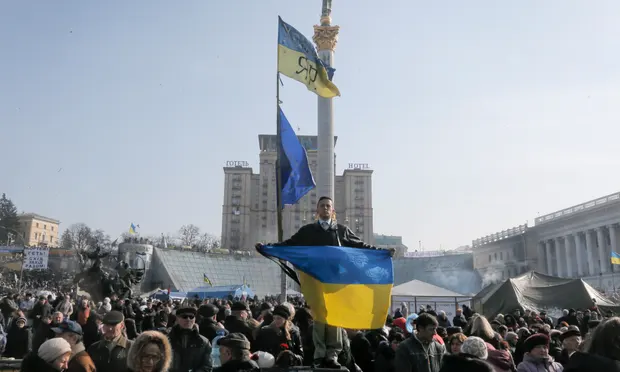 An anti-Yanukovych protester holds a Ukrainian flag in Kyiv's Independence Square