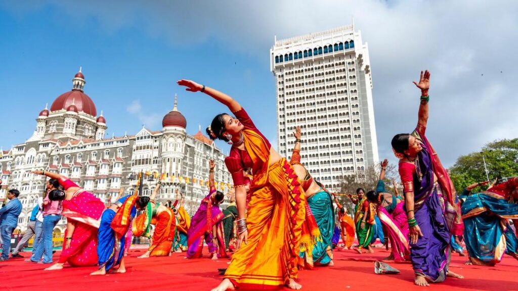 Women wearing traditional Nauvari sarees perform yoga